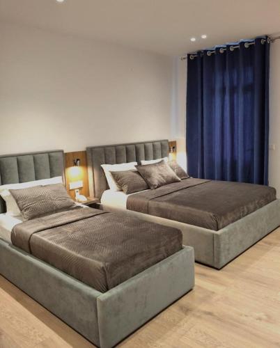 two beds in a bedroom with blue curtains at HOTEL KRISTAL in Vlorë