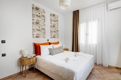 a bedroom with a white bed and a window at VERSA by Apiro Syros in Ermoupoli