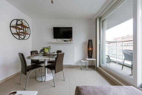 a dining room with a table and chairs and a tv at Casiola - Spacious & light apartment with double terrace in Nieuwpoort