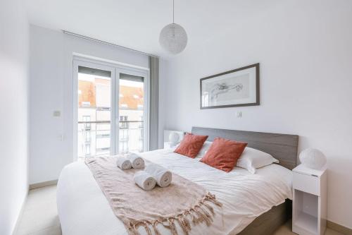 a white bedroom with a large bed with two towels at Casiola - Spacious & light apartment with double terrace in Nieuwpoort