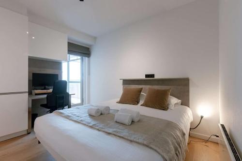 a bedroom with a large white bed with towels on it at Casiola - Nice apartment close to the beach with parking in Nieuwpoort