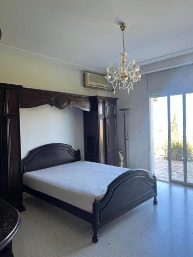 a bedroom with a large bed and a chandelier at Villa Horizon & Pool Bizerte in Bizerte