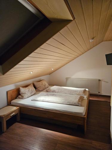 a bed in a room with a wooden ceiling at Lieblingsplatz in Ebersburg