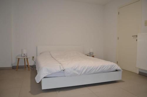 a white bed in a white bedroom with a white wall at Cozy Apartment for 4 Steps from the Beach in Ostend