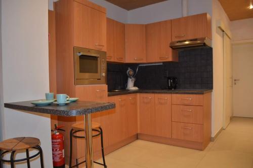 a kitchen with wooden cabinets and a counter with stools at Cozy Apartment for 4 Steps from the Beach in Ostend