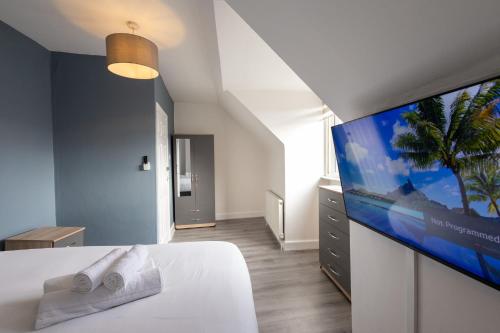 a bedroom with a white bed with a flat screen tv at Large 4-Bedrooms Corporate Flat, Free Parking - Amazing Location in Leavesden Green