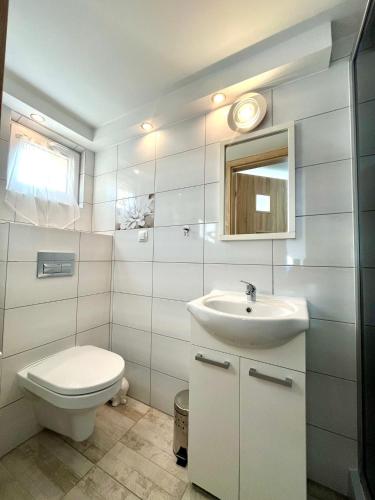 a white bathroom with a toilet and a sink at Pokoje w Kołobrzegu in Kołobrzeg