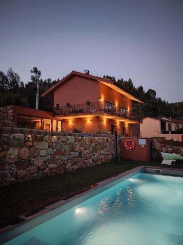 a house with a swimming pool in front of a house at Fragas do Cabril Eco & Wellness Lodge in Lousã