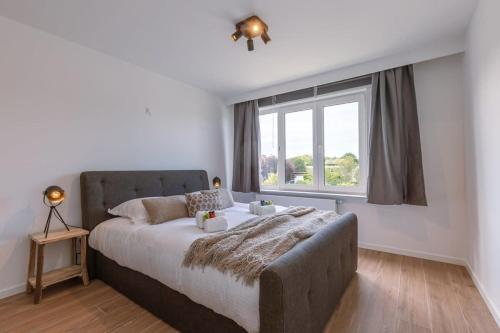 a bedroom with a large bed and a window at Casiola - Cosy apartment with vintage interior in De Haan