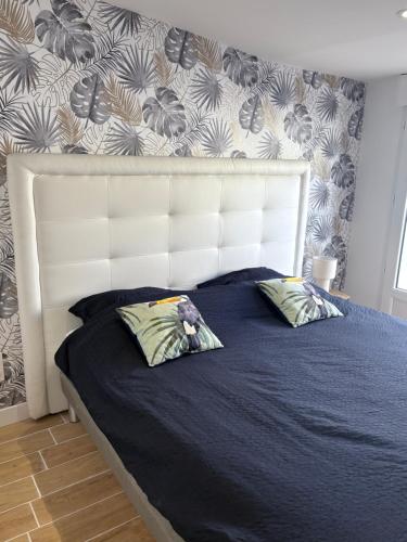 a bed with a white headboard and two pillows at Lodge La Forêt in Les Sables-d'Olonne