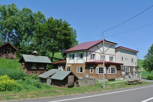 una casa grande al lado de la carretera en Pension Megumiyuki en Biei