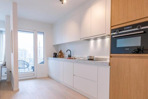 a white kitchen with a sink and a stove at Casiola - Luminous family apartment with magnificent view in Ostend