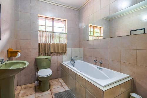 a bathroom with a tub and a toilet and a sink at Flamboyant Guesthouse in Bela-Bela