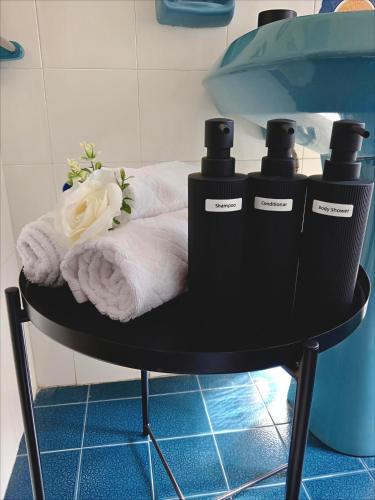 a black table with three bottles of soap and towels at Suite Fronte Mare Senigallia- Terrazza Esclusiva sulla Spiaggia in Senigallia
