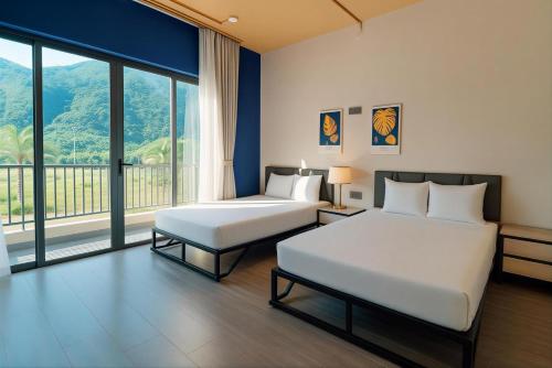 a hotel room with two beds and a large window at Sonasea Vân Đồn - Centraltique Seaside in Quang Ninh