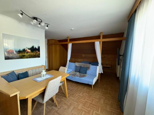 a living room with a table and a blue couch at Pferdehof Rupitsch - Haus Carina in Weissensee
