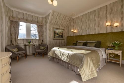 a bedroom with a large bed and two chairs at Windlestraw Guesthouse in Walkerburn