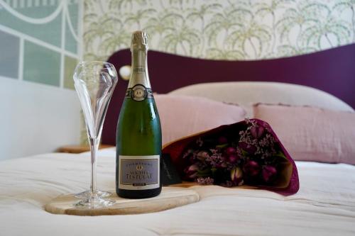 a bottle of wine and a glass on a bed at Le Cocon Spa proche Puy DuFou in Mesnard-la-Barotière