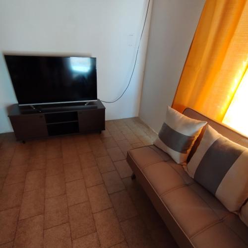 a living room with a couch and a flat screen tv at Alquiler por Día SyA Cipolletti in Cipolletti