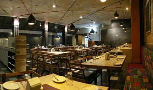 Un comedor con mesas y sillas en un restaurante. en Hotel Zorba Inn, en Kolhapur