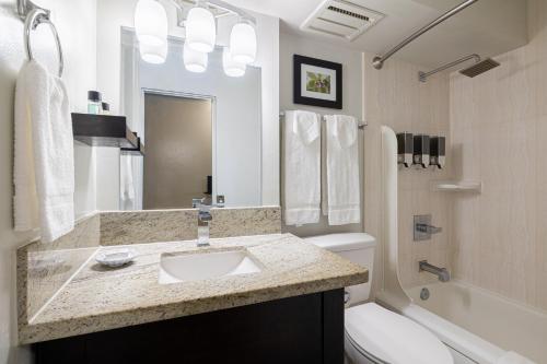 a bathroom with a sink and a toilet and a tub at Skyline Island Colony Hotel in Honolulu