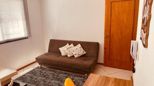 a living room with a brown couch with pillows at Aconchego - com Garagem in Santa Maria