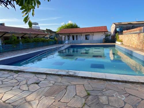 a large swimming pool with a stone walkway around it at Pousada Costa Azul in Paulista