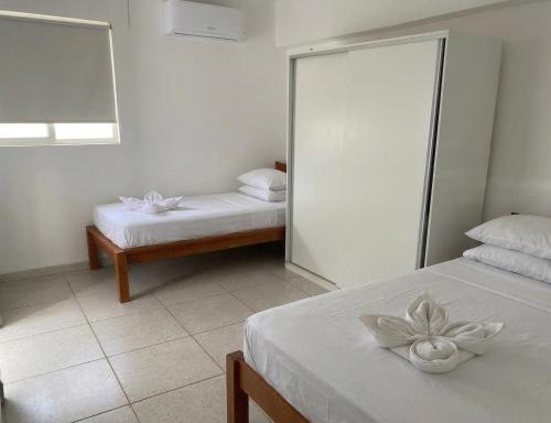 a white room with two beds and a mirror at Pousada Costa Azul in Paulista