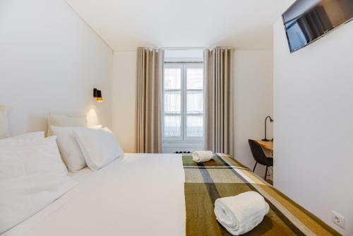 a bedroom with a white bed and a desk at Correio Velho Hotel in Lisbon