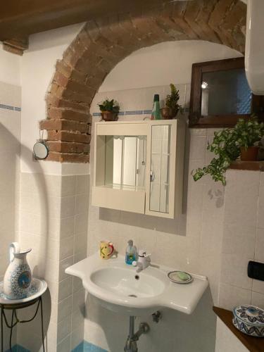 a bathroom with a white sink and a mirror at Finestra sulla Val D'Orcia in Campiglia dʼOrcia