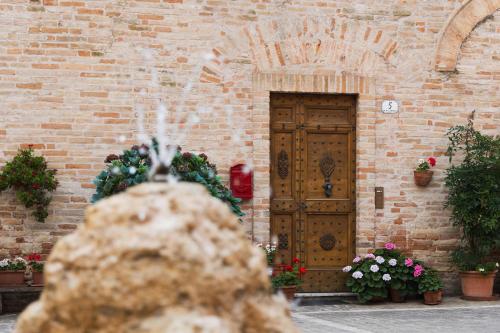a brick building with a wooden door and flowers at Casa Montefiori in Montefiore dellʼAso