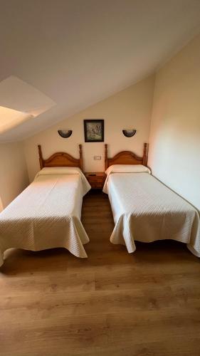 two beds in a room with wooden floors at Hotel Gavitu in Celorio