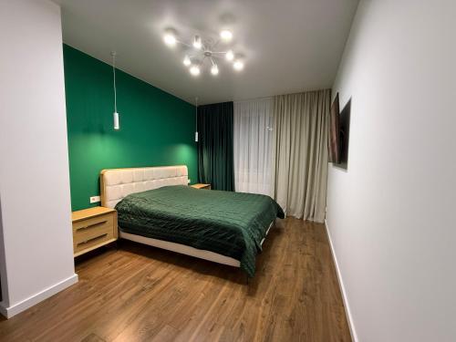 a bedroom with a bed with a green wall at GS Green Apartment in Starokostyantyniv