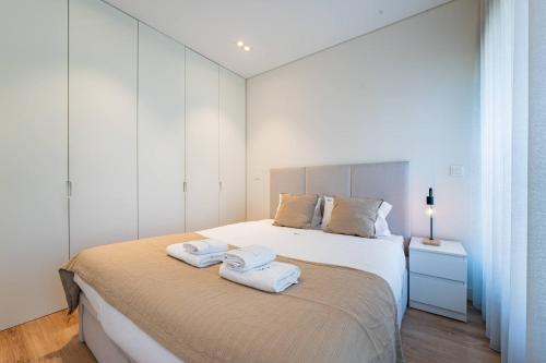 a bedroom with a bed with towels on it at Antas Park Concept Lifestyle With Pool in Porto