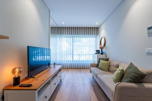 a living room with a couch and a flat screen tv at Antas Park Concept Lifestyle With Pool in Porto