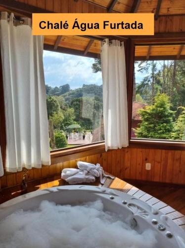 a bath tub in a room with a window at Pousada Ana Terra in Monte Verde