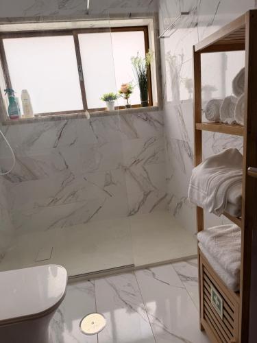 a bathroom with white marble walls and a window at Casa São Domingos 2 in Lousada