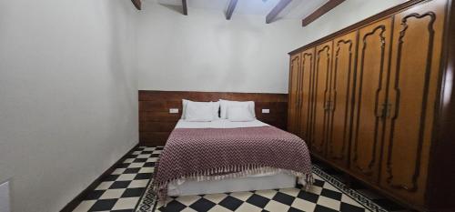 a bedroom with a bed with wooden cabinets and a checkered floor at La Barbacoa in Dos Pinos