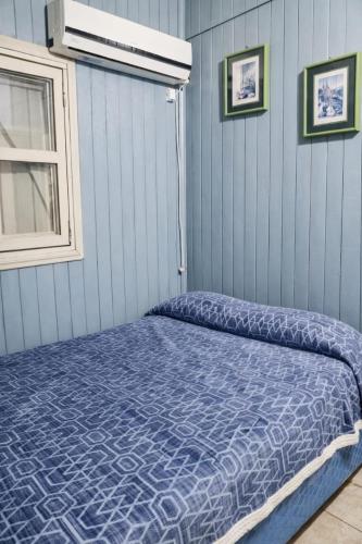 a bedroom with a bed with a blue comforter at Cabaña 3 del Puerto Gol in Santo Tomé