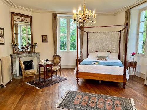 a bedroom with a canopy bed and a fireplace at Le logis de Lasteyrie in La Rochebeaucourt-et-Argentine
