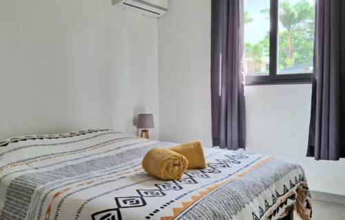 a bedroom with a bed with a yellow pillow on it at Location saisonnière in Petit-Bourg