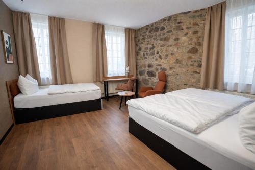 a hotel room with two beds and a chair at Hotel und Restaurant Hohe Schule in Herborn