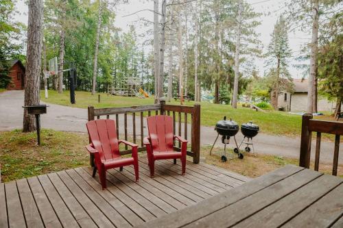 two red chairs and a grill on a wooden deck at Old Stoney's Walleye- Pet Friendly in Arbor Vitae
