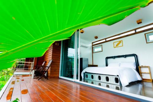 a bedroom with a bed and a green roof at Baan Boom Boxes Eco Friendly Resort in Mae Nam