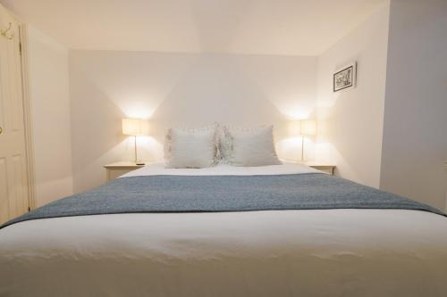 a bedroom with a large white bed with two lamps at Bains Closs, Shetland Islands in Lerwick