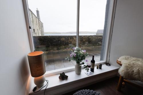 a window with flowers and wine bottles on a table at Bains Closs, Shetland Islands in Lerwick