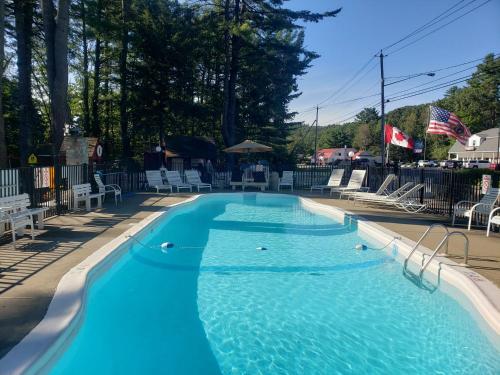 a large blue swimming pool with chairs and trees at Do-Rest Court in Lake George