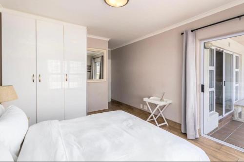 a white bedroom with a bed and a table at Luxurious 2Bed ,Iconic Views Mountain& Beach in Big Bay