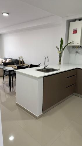 a white kitchen with a sink and a table at Portal Patagónico in Puerto Madryn