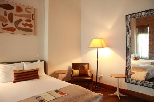 a bedroom with a bed and a mirror and a chair at Las Clementinas in Panama City